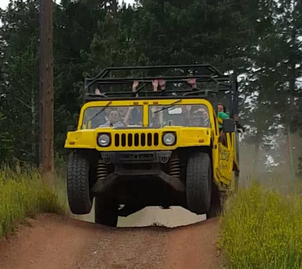 Yellow Hummer with both front wheels off the ground going off a jump
