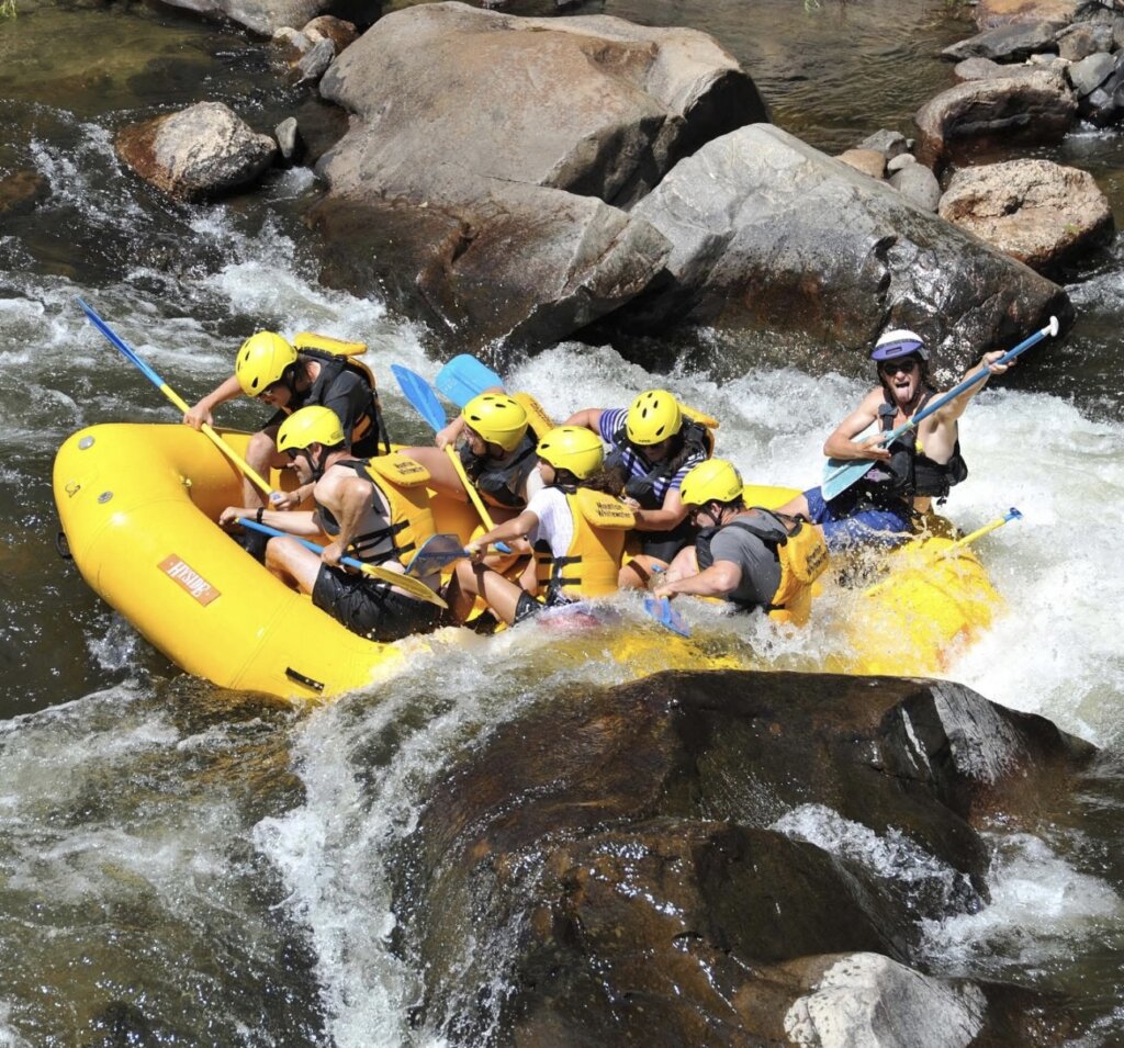 Rafters brace for a wave through a sluice box in between two giant boulders